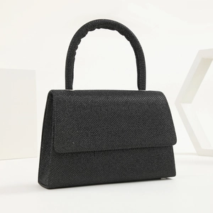 Detail of a black sequined evening clutch bag with top handle and shiny glitter texture