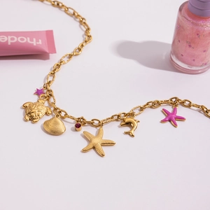 Detail view of gold ocean charms featuring starfish, shells, and a turtle on a necklace