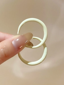 Close-up of cream yellow chunky hoop earrings in minimalist style held by hand
