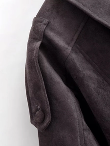Détail d'une veste en daim marron foncé avec boutons assortis et texture de couture fine