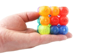 Macro detail of hand holding a 3x3 colorful magnetic sphere puzzle cube toy