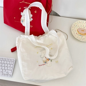 Detail of red and cream canvas tote bags with cute embroidery and drawstring closure