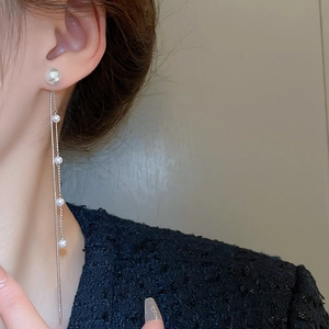 Close-up of elegant pearl tassel earrings with silver chain on model showcasing style