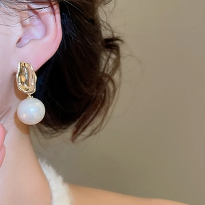Detail of round pearl drop earring with hammered gold base on a model's ear