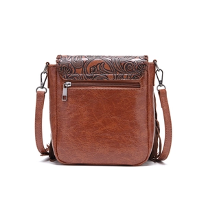 Detail of brown vintage crossbody bag with embossed floral texture and side tassels