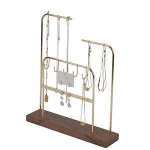 Detail of metal jewelry organizer with gold hooks and walnut wood base for earrings