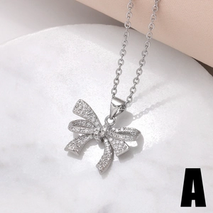Silver bow necklace with zircon inlay on white marble and pink satin background