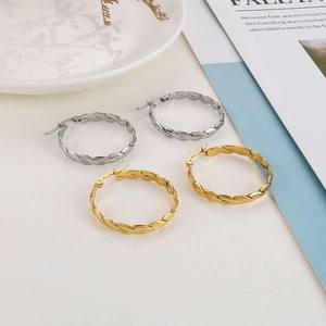 Detail of twisted rope hoop earrings in gold and silver finish on a minimalist background