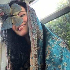 Elegant ethnic paisley print shawl with decorative tassels shown in natural window light