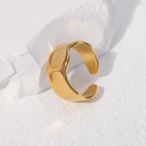 Close-up of golden irregular hammer pattern ring on a white stone decorative block