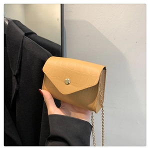Detail of khaki crocodile pattern square bag with gold chain strap and metal clasp