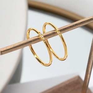 Minimalist 18K gold plated titanium ring with small zircons on a jewelry display stand