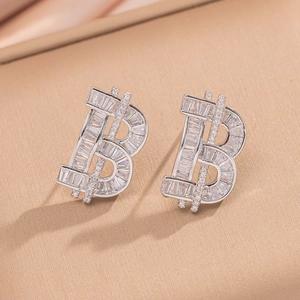 Luxury silver-tone letter B stud earrings with sparkling crystals on silk background