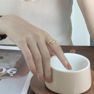 Detailed view of gold lava texture ring with small diamonds on model's finger