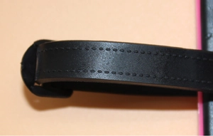 Detailed macro view of black faux leather strap with reinforced stitching on luggage tag