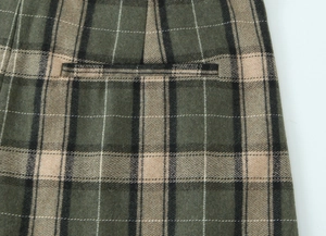 Détail du pantalon en laine à carreaux vert olive montrant la poche et la texture du tissu