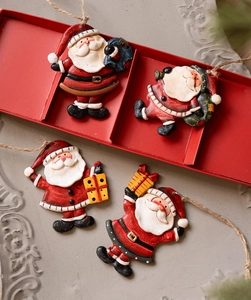 Detail of four vintage resin Santa Claus ornaments with jute ropes in a red display tray