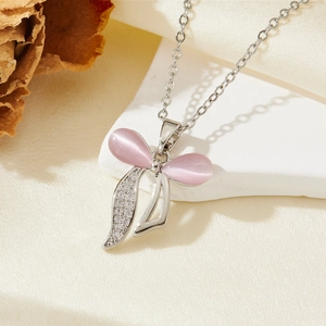 Détail du collier nœud avec pierres œil de chat roses et zircons sur support en pierre blanche