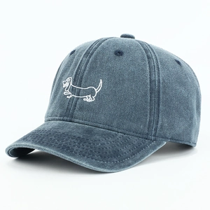 Close-up of detailed white dachshund embroidery on washed blue denim baseball cap