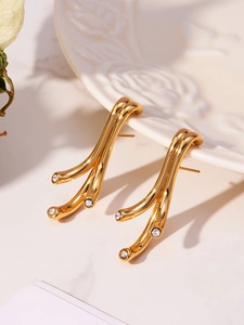 Détail de boucles d'oreilles dorées en forme de branche avec zircons sur assiette en relief