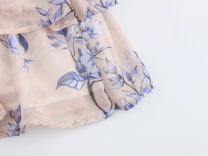 Gros plan détaillé du tissu en mousseline fleurie rose avec motifs bleus et plis