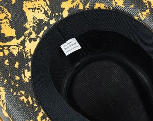 Detail view of woven paper beach hat featuring breathable mesh lining and 100% paper label