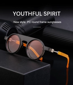 Detail shot of round frame sunglasses in black and orange on a textured surface