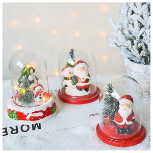 Detail of Christmas glass globes with Santa figures and warm LED fairy lights on a table