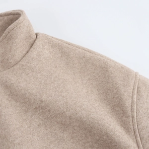 Detailed macro view of the light brown wool blend fabric and shoulder stitching on jacket