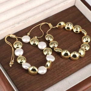 Dettaglio di bracciali intrecciati con perle e sfere dorate con chiusura regolabile in legno