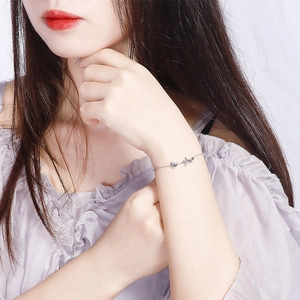 Silver heartbeat pulse bracelet featuring a blue heart gemstone on a model's wrist