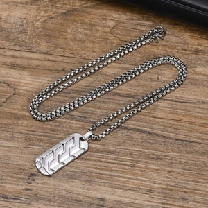 Detail of silver stainless steel rectangular pendant with tire tread pattern on wood