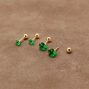 Macro shot of green zircon stud earrings with gold four-prong setting and screw back