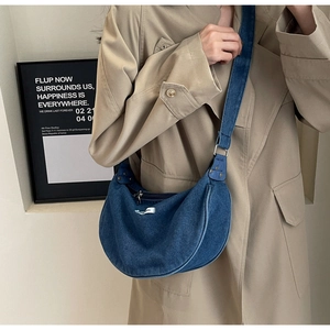 Close-up of blue denim crescent bag worn with a khaki trench coat for a casual look