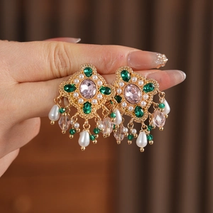 Gros plan de boucles d'oreilles vintage avec gemmes roses, zircons et perles pendantes