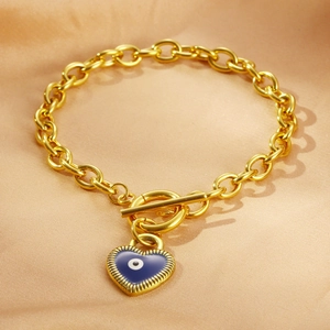 Detail eines Goldkettenarmbands mit OT-Verschluss und blauem herzförmigem Evil-Eye-Anhänger