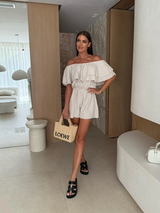Detail of ruffle off-shoulder neckline and textured cream fabric on summer romper