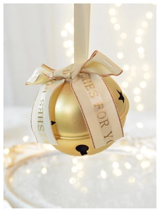 Close-up of golden metal Christmas bell with beige ribbon and Best Wishes text