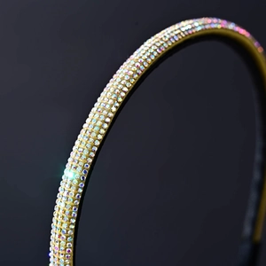 Macro shot of sparkling AB rhinestones on a slim gold headband with light flare