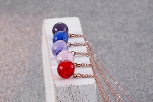 Macro detail of multi-colored faceted crystal pendants on rose gold clavicle chains