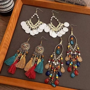 Detailed close-up of Bohemian tassel earrings with beads and metal discs on a dark tray