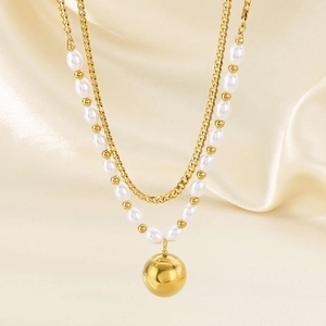 Detail of double-layer necklace with golden metal ball pendant and white pearls on satin