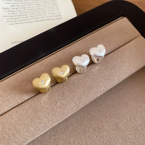 Macro view of gold and silver brushed heart earrings with zircon star detailing