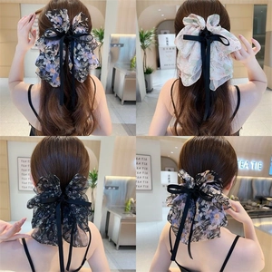 Detailed back view of four elegant floral chiffon bow hair claws with ribbons on model hair