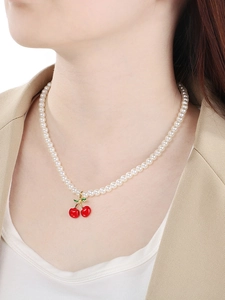 Close-up of model wearing a sweet red cherry pendant necklace with white pearls and gold accents