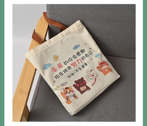 Close-up of canvas tote bag with brown straps and inspirational cartoon print on a sofa