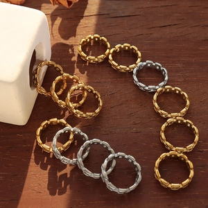 Minimalist gold and silver hollow chain rings arranged in a heart shape on wood