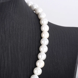 Close-up of elegant white pearl necklace on a black textured bust stand with rich luster