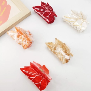 Flat lay of five acetate leaf hair claws with marble patterns and gold vein details