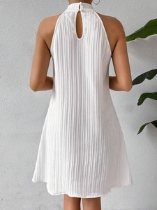 Back view of white halter dress with vertical pleated fabric and open back detail